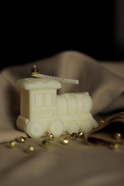 Figurină din ceară de soia în formă de trenuleț, model Nivalis, colecția Christmas Candla, decorată cu detalii fine și așezată pe fundal bej.